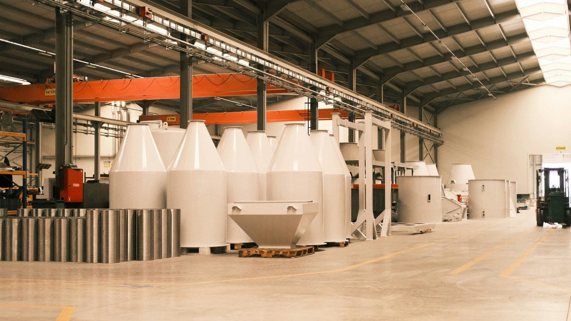 Stainless steel mixing reactors and bulk storage tanks on a formulation plant floor.