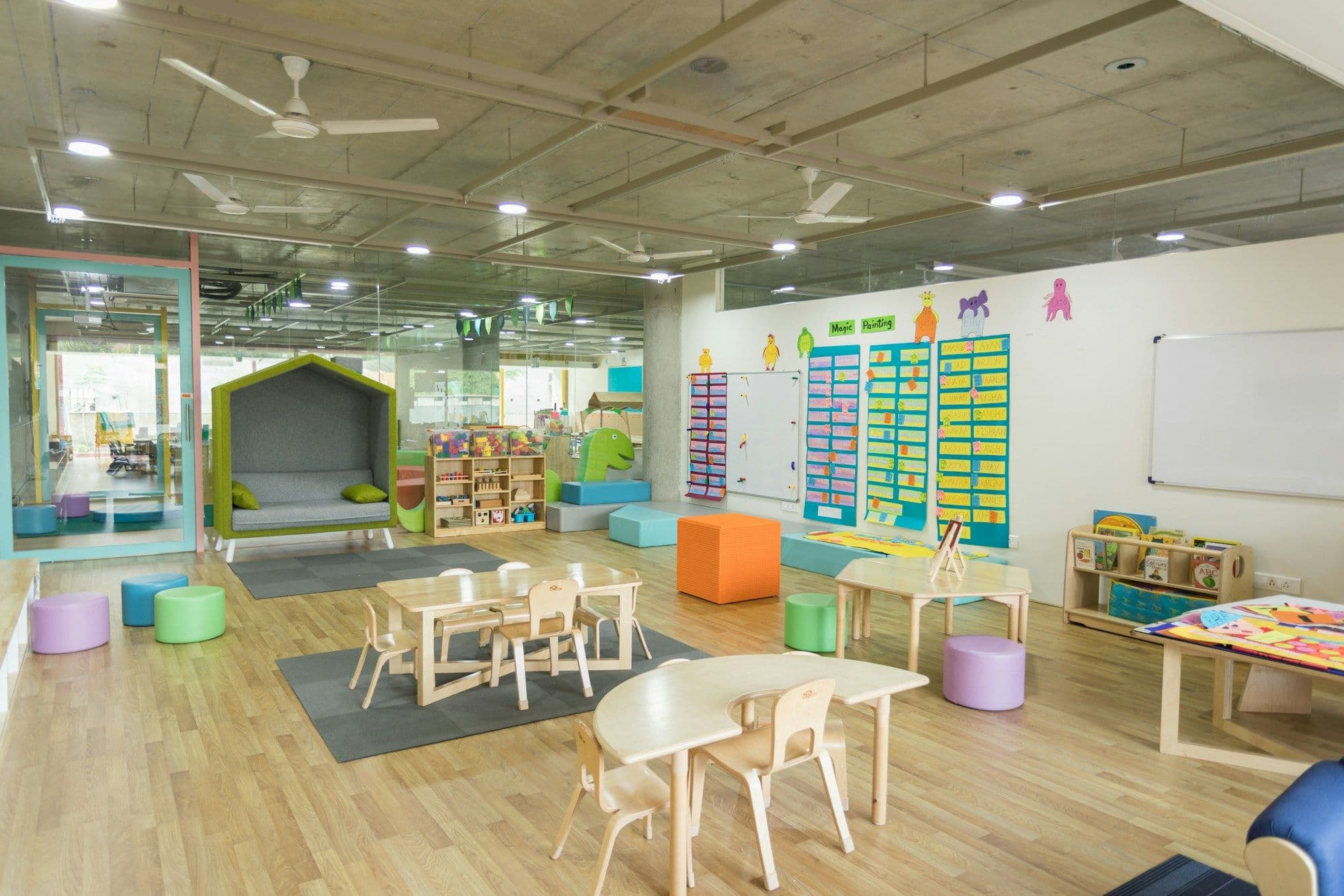 Bright kindergarten classroom with small tables, chairs and play areas