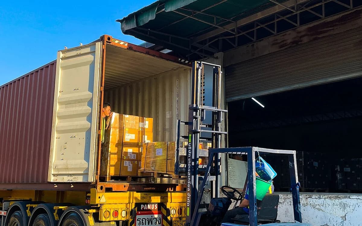 Forklift loading palletized 25L cleaner drums into shipping container