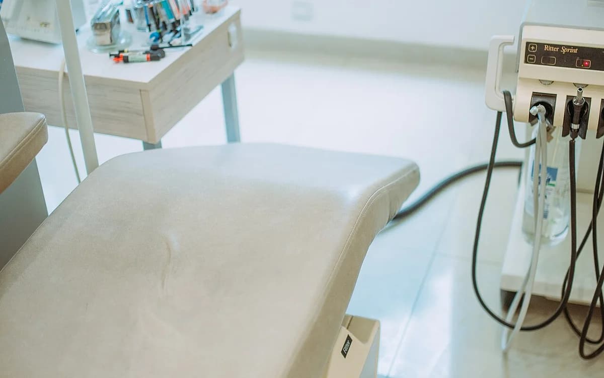 Modern dental clinic treatment room with dental chair, overhead lamp, and modular instrument cabinetry
