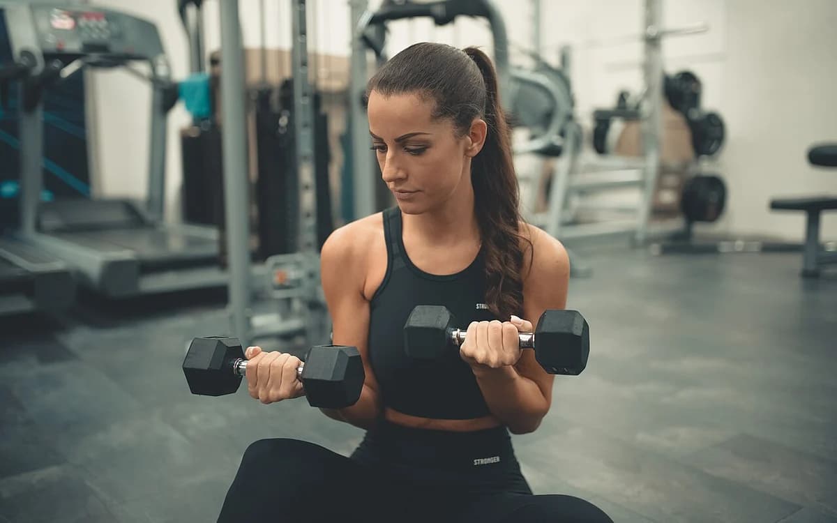 Athlete training with dumbbells on a commercial gym floor