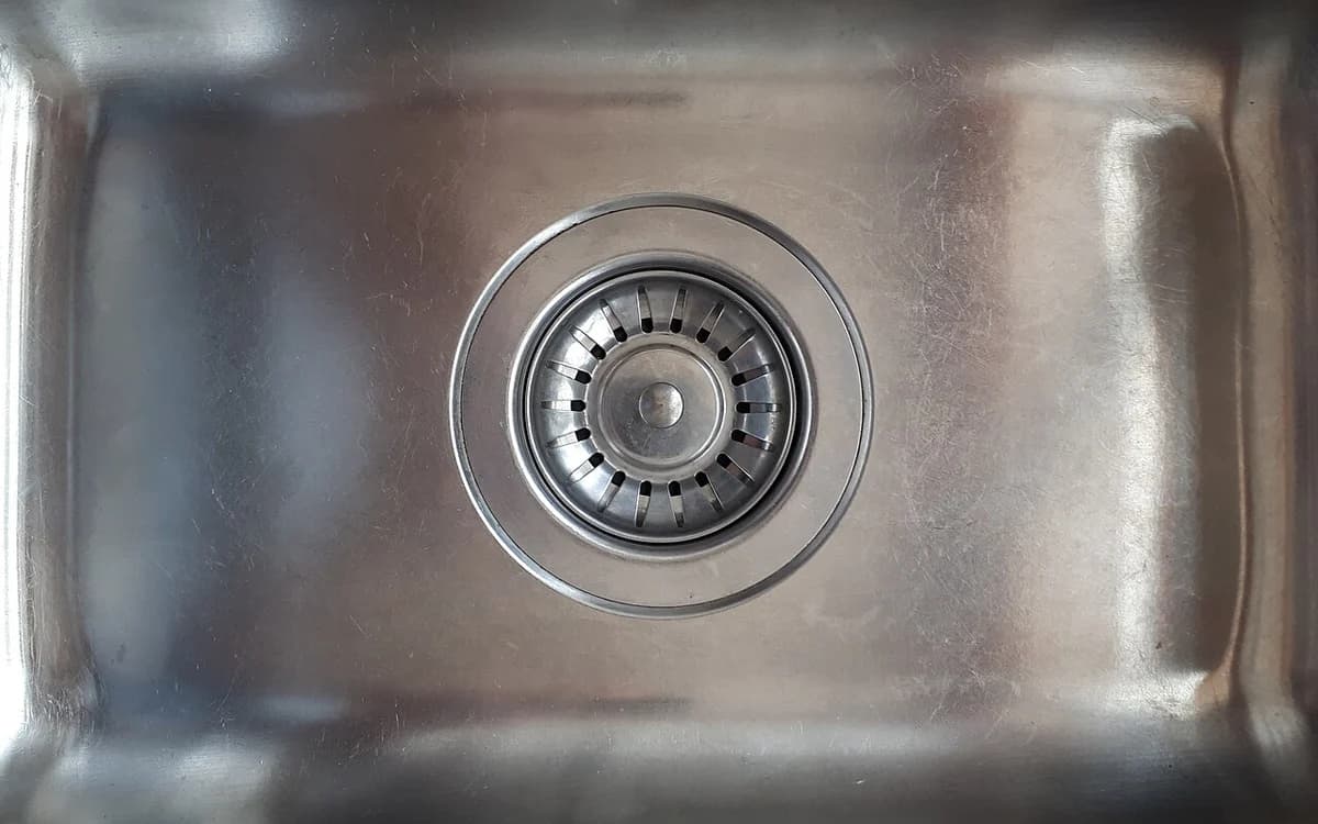 Commercial kitchen stainless-steel sink drain and strainer leading to grease interceptor