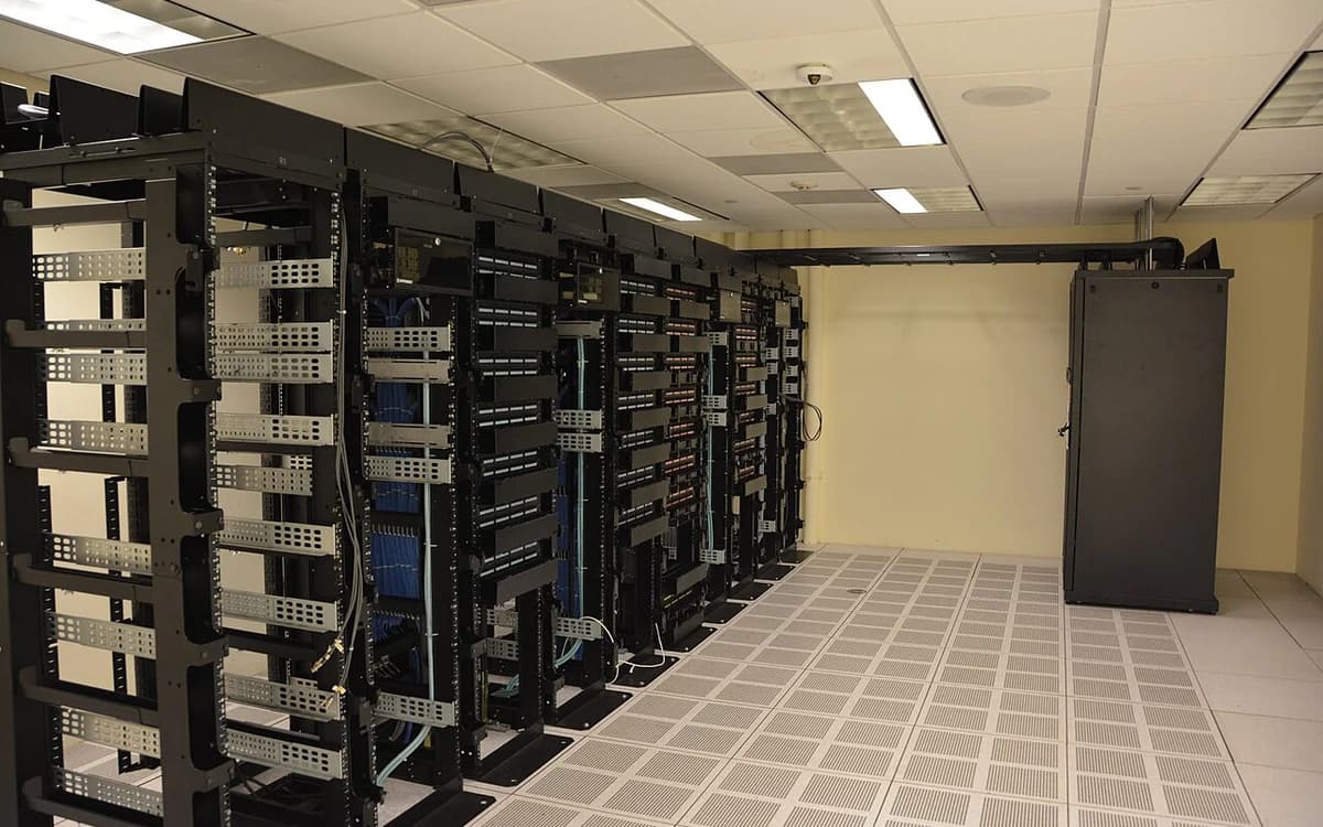 Data center cold aisle corridor with high-density server racks and perforated floor tiles