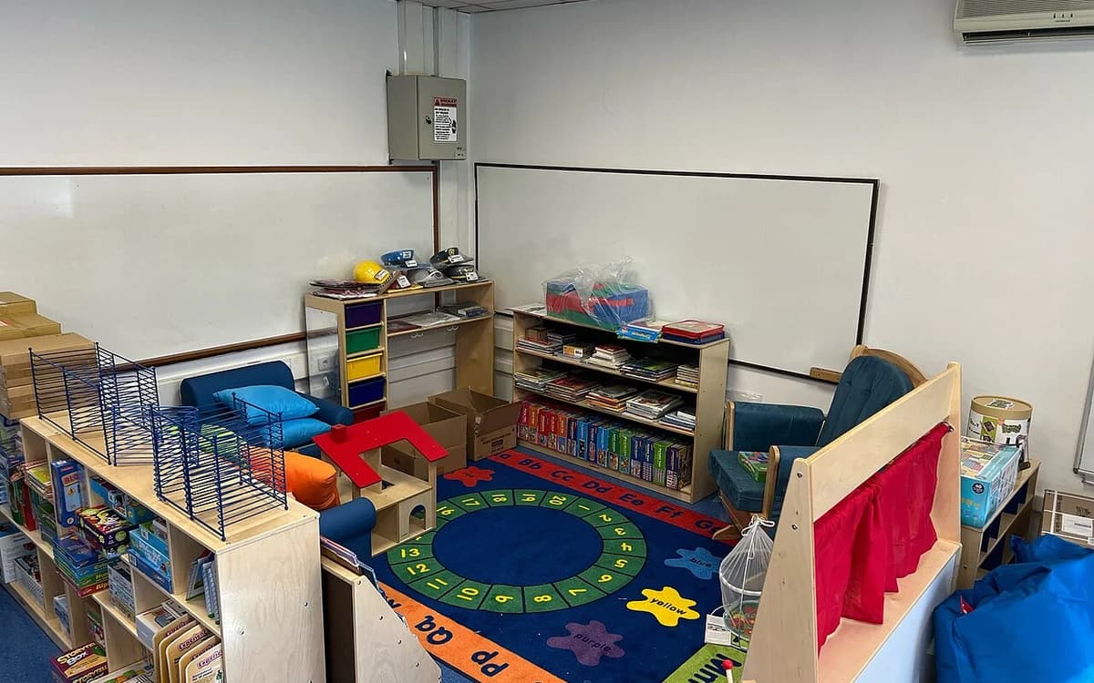 Pre-K kindergarten classroom outfitted with low-height wooden tables, chairs, and storage cubbies