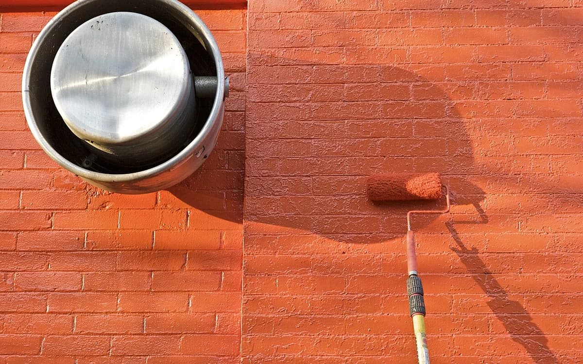 Applying architectural latex wall paint with a roller onto commercial drywall
