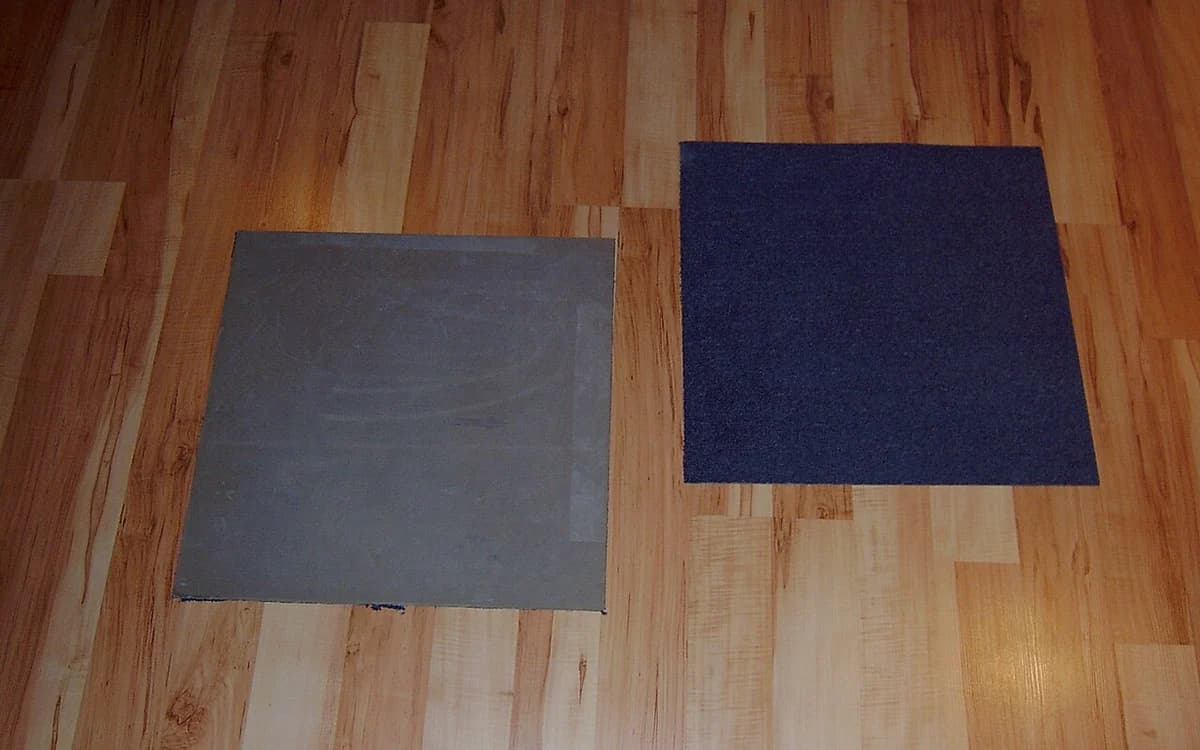 Modular commercial carpet tiles showing textile face pile and synthetic backing layer