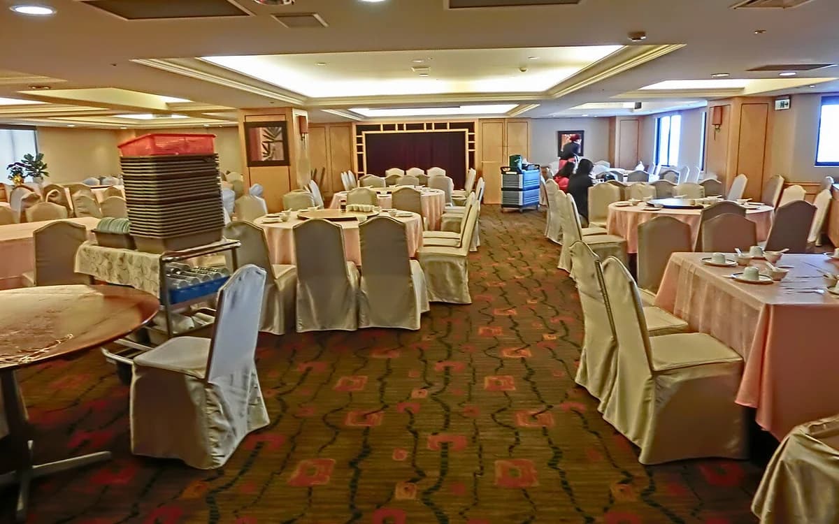 Hotel banquet dining room with round banquet tables, upholstered chairs, and carpet