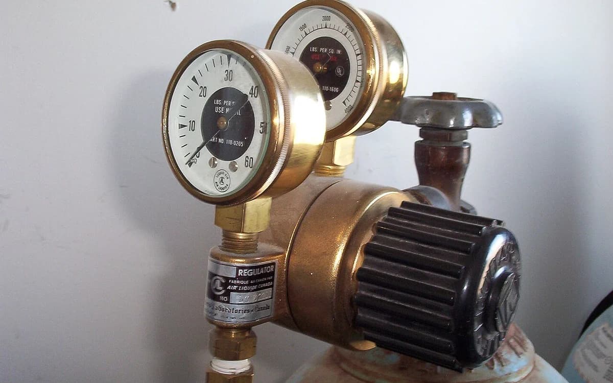 Technician calibrating pneumatic air pressure regulator gauge on spray equipment