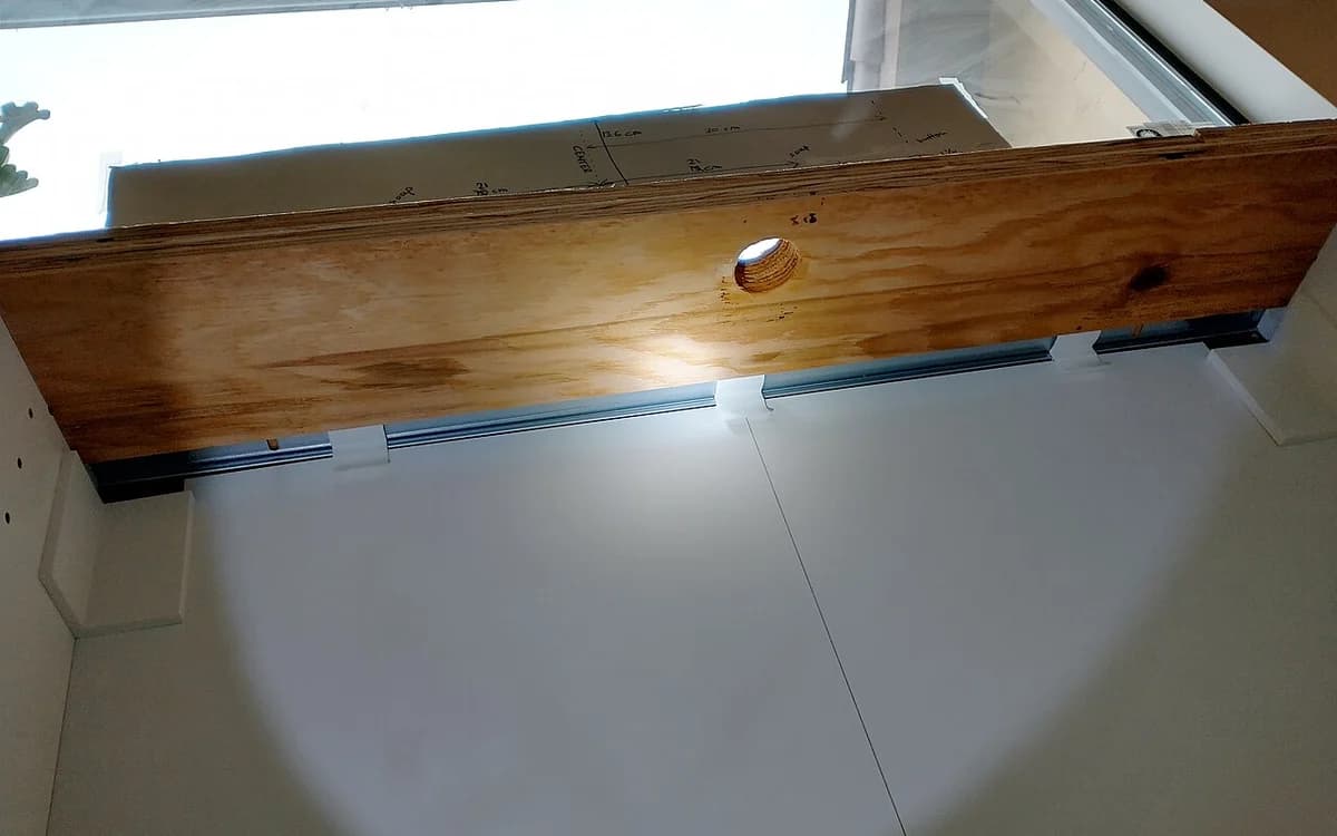 Kitchen sink base cabinet interior showing water supply pipes and drain cut-outs