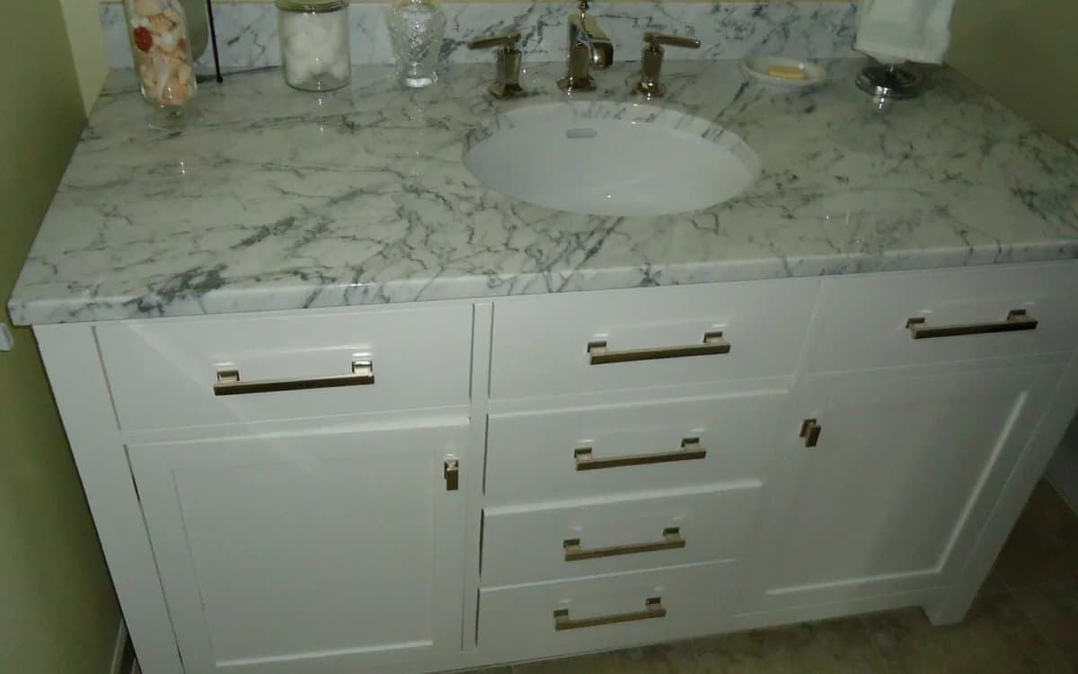Bathroom vanity cabinet with sink basin, plumbing cavity, and storage drawers