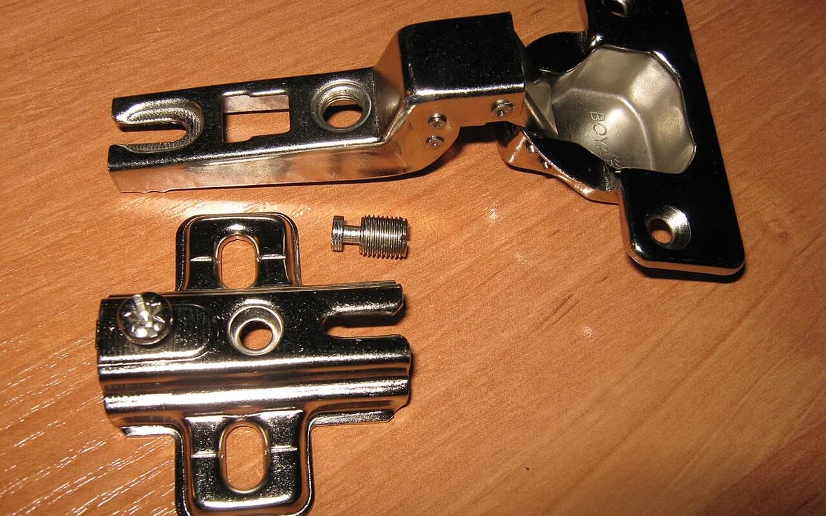 Close-up of a 35 mm slide-on cup hinge mounted inside a bored particleboard cabinet door cavity