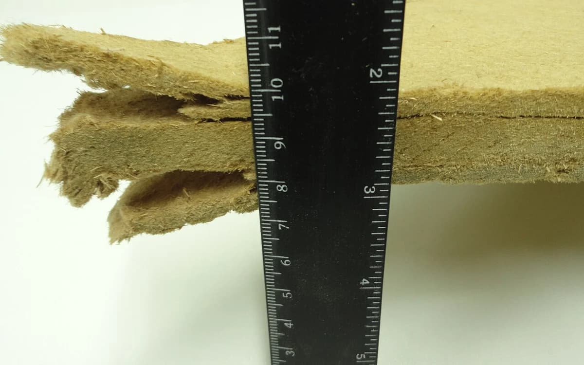 Macro cross-section of stacked raw medium-density fiberboard panels showing porous saw-cut edges