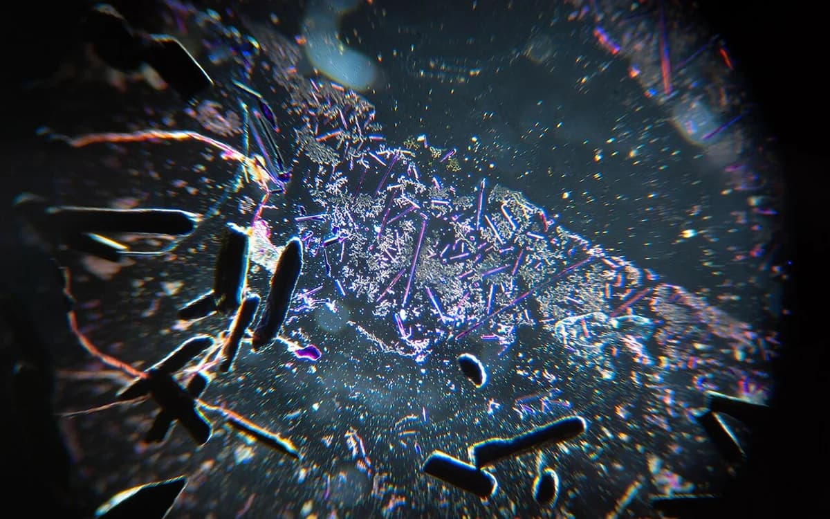 Darkfield macro view of vibrant purple potassium permanganate crystals