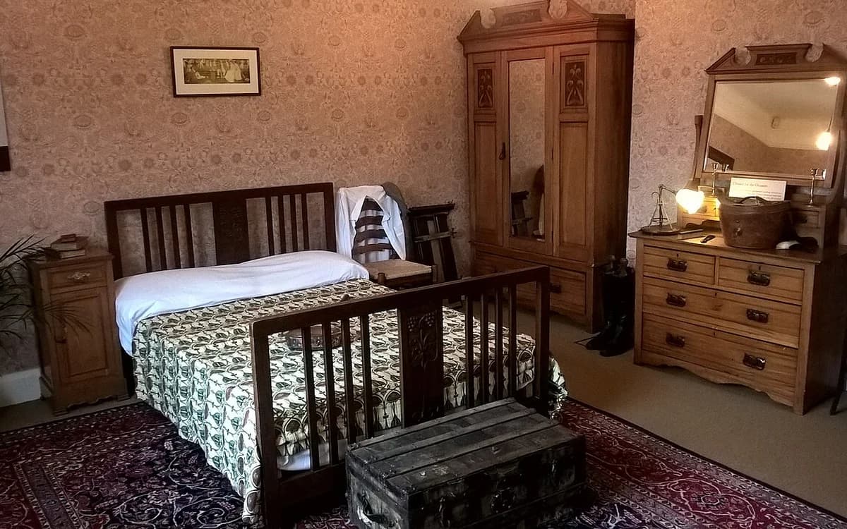 Furnished bedroom with wooden wardrobe, chest of drawers, and bed