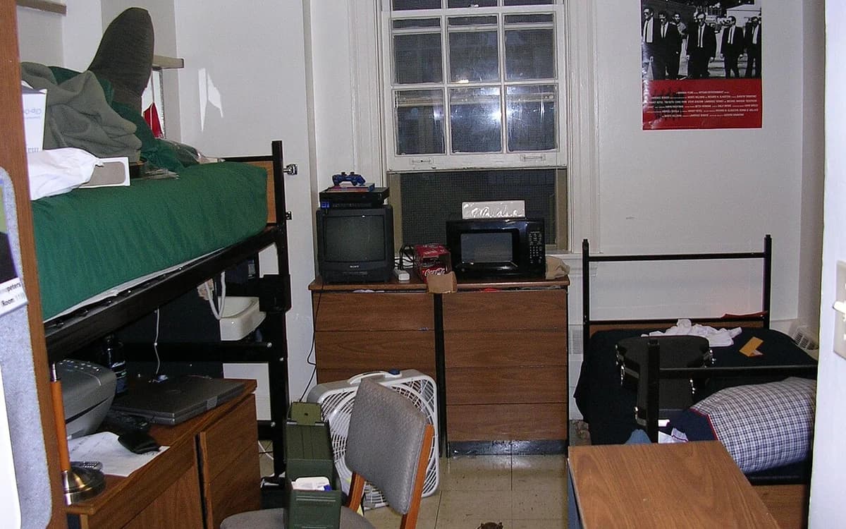 Student dormitory room with wooden bunk beds, mattresses, and storage lockers