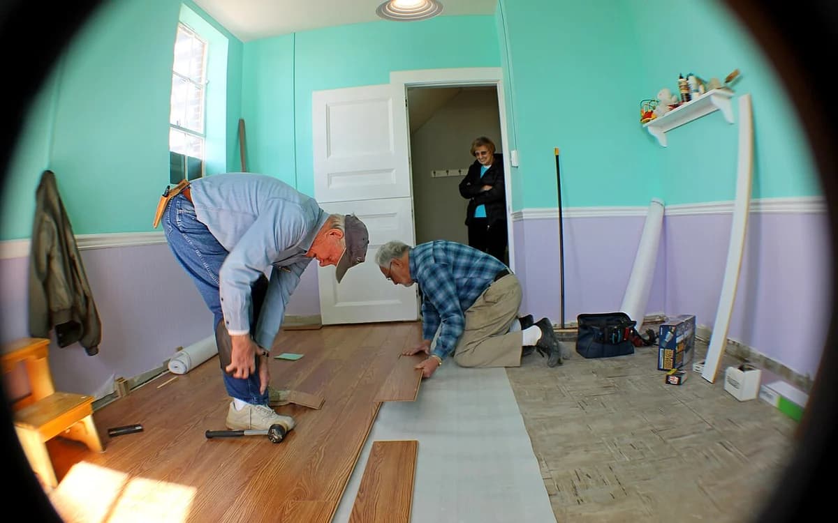 Floating laminate wood flooring installation showing underlayment and perimeter baseboard expansion gaps