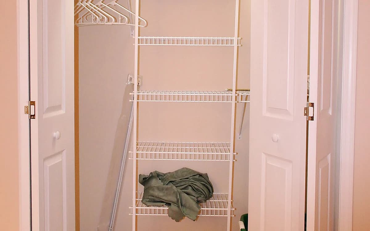 Built-in wooden wall closet showing open shelving compartments and lower drawers